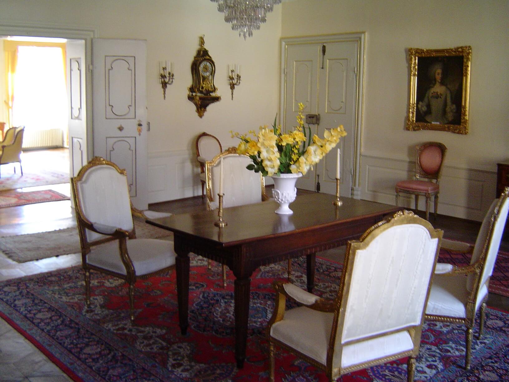 ein Esstisch mit Stühlen und eine Vase mit Blumen darauf